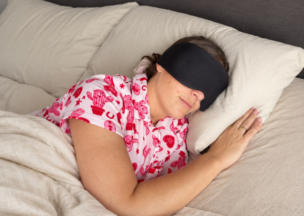 Woman sleeping on her side wearing the black Gravity weighted sleep mask